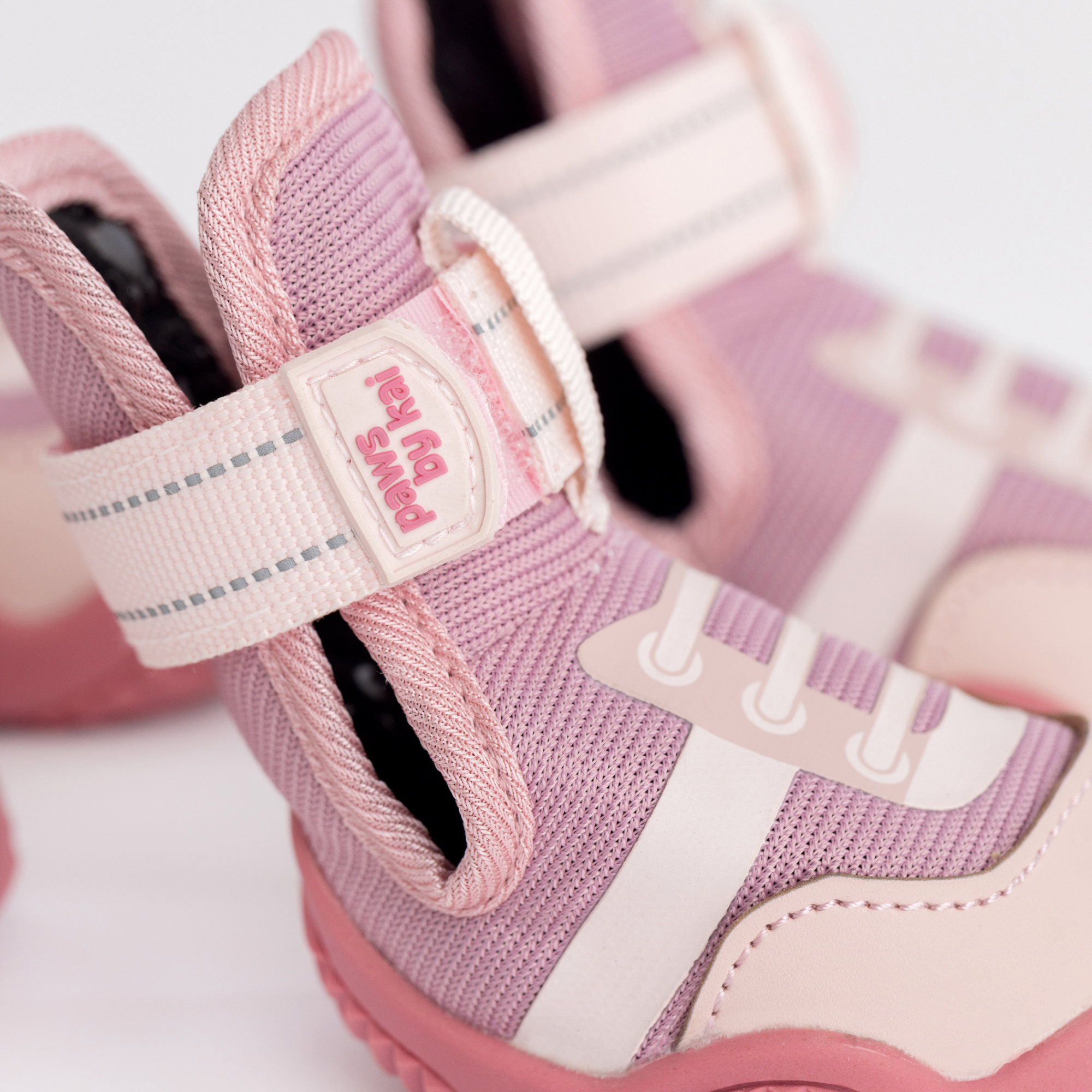 Pink and white hook-and-loop strap with logo patch on dog sneaker