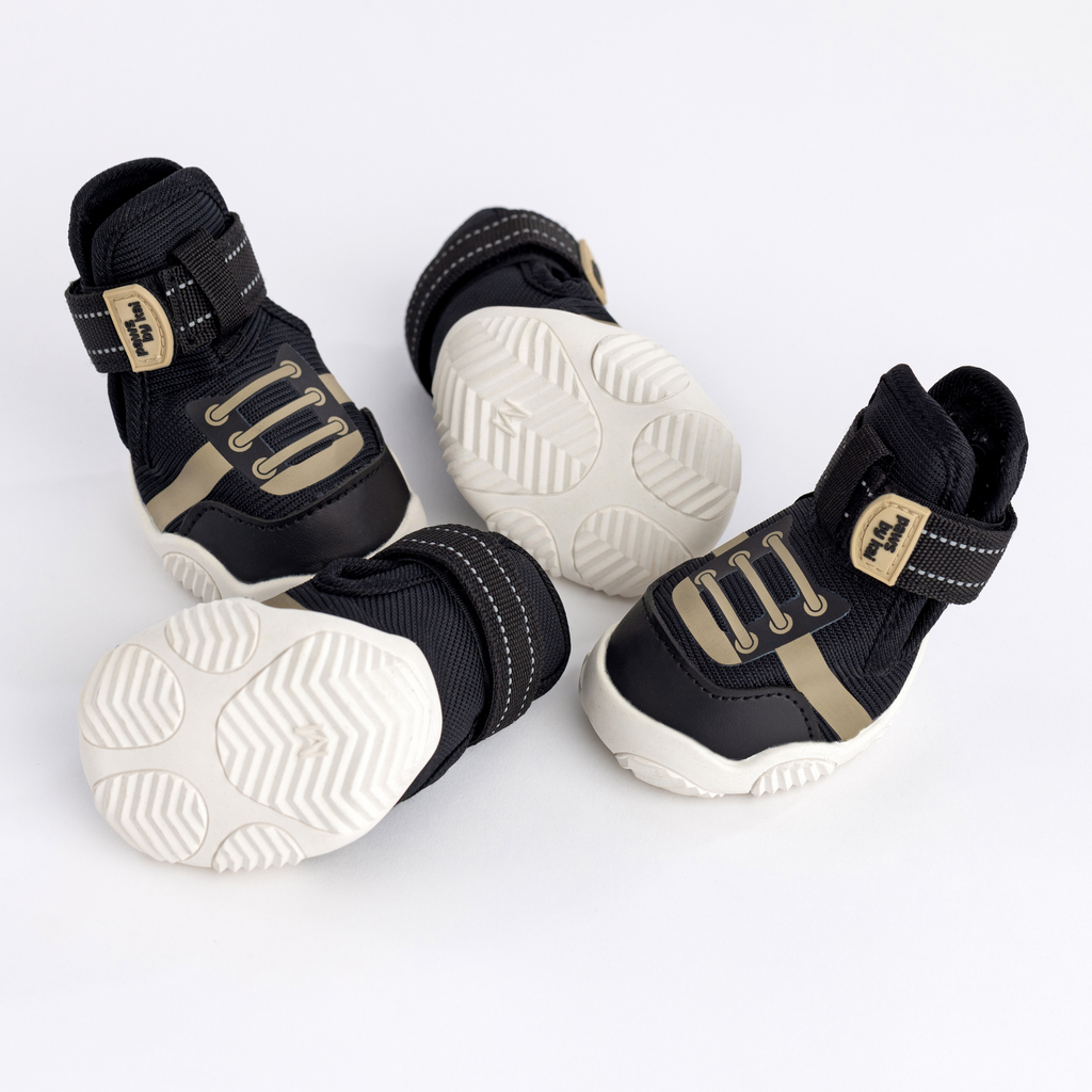 Black dog sneakers showing side, front, and outsole tread with hook-and-loop straps