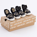 Black dog sneaker with hook-and-loop straps, padded collar, and beige logo patch