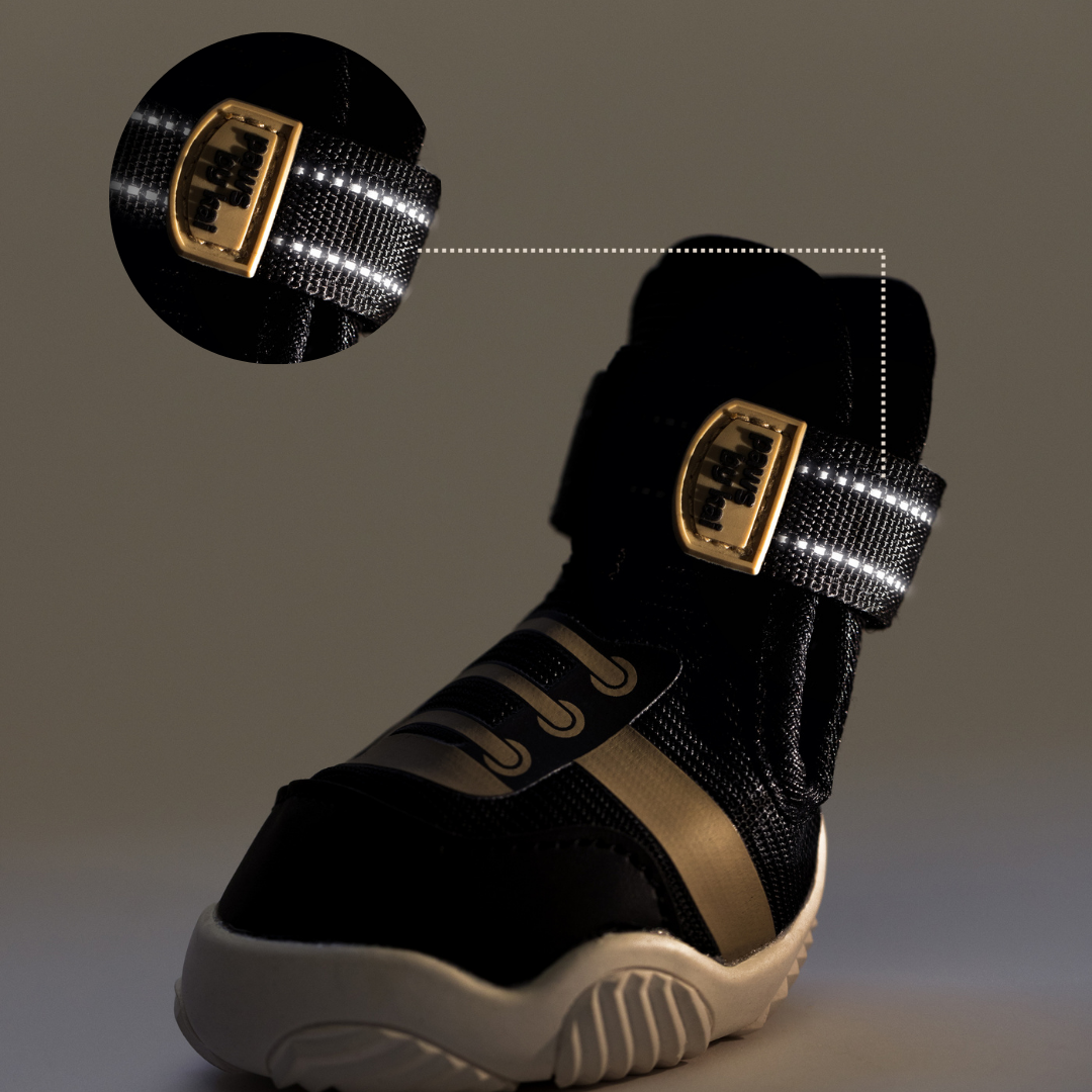 Black dog sneaker with mesh upper, beige side panel, and hook-and-loop closure
