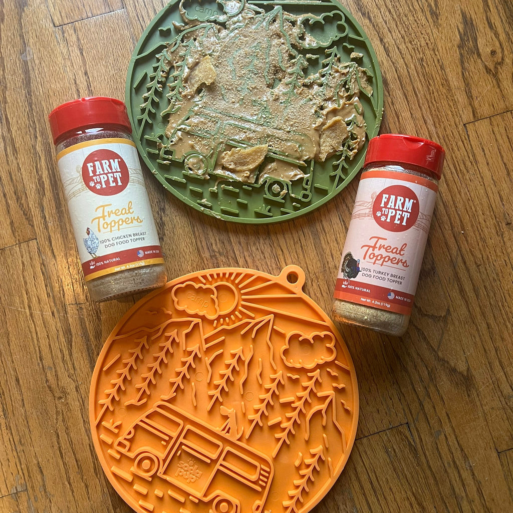 Green and orange dog lick mats with raised patterns, with treat bottles nearby.