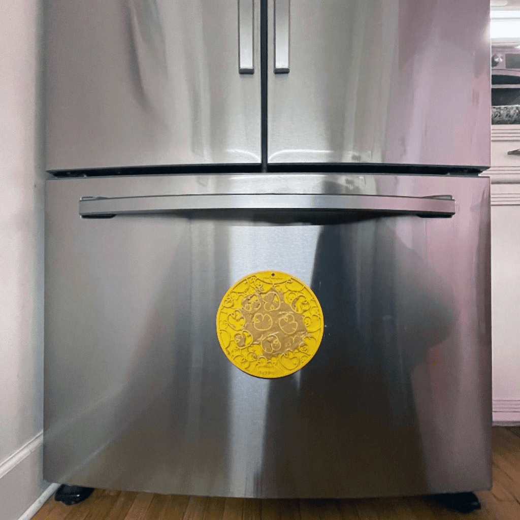 Yellow circular suction-cup dog lick mat attached to a stainless cabinet door