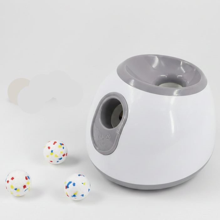 Automatic dog ball launcher close-up with gray side opening and three scattered balls