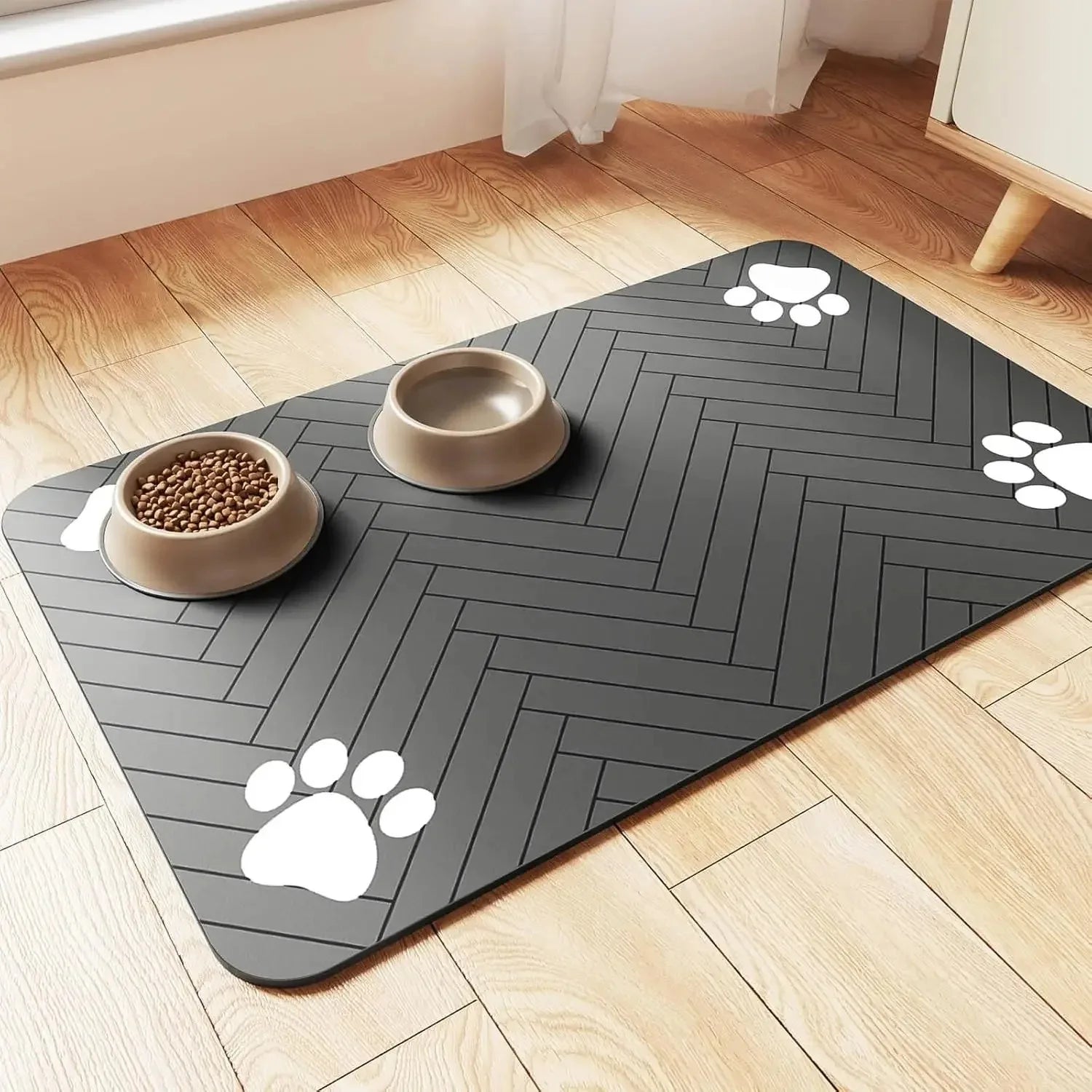 Rectangular pet feeding mat in dark grey with white paw prints and two bowls on top