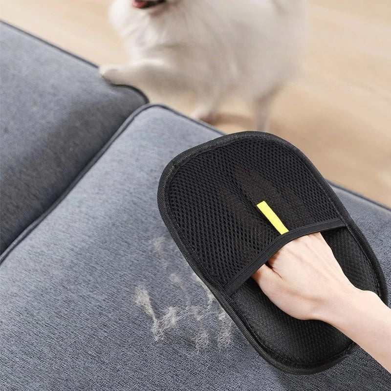Pet hair remover glove with black mesh pad and yellow tab, worn by hand