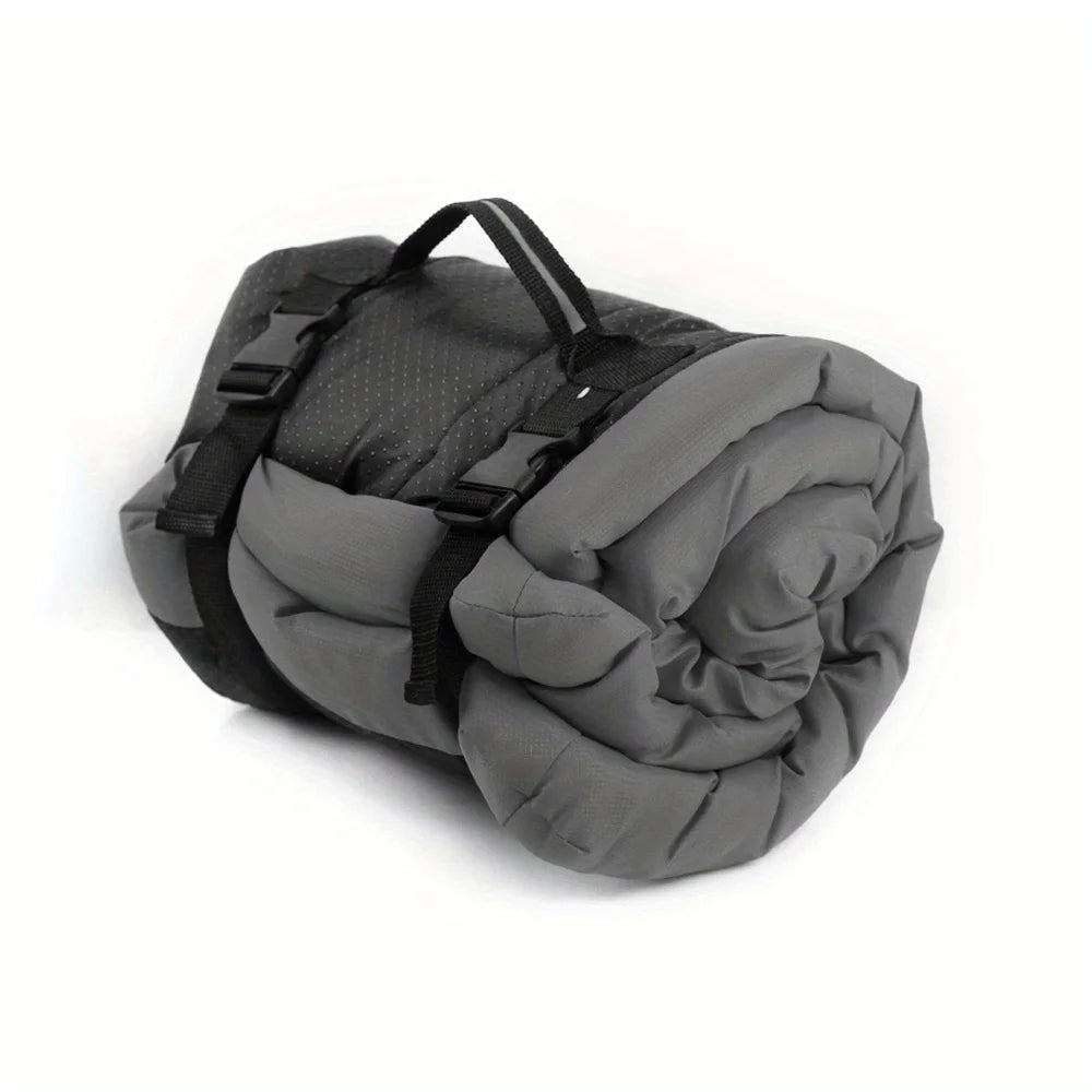 Pet bed cushion in gray, rolled up with black carry straps