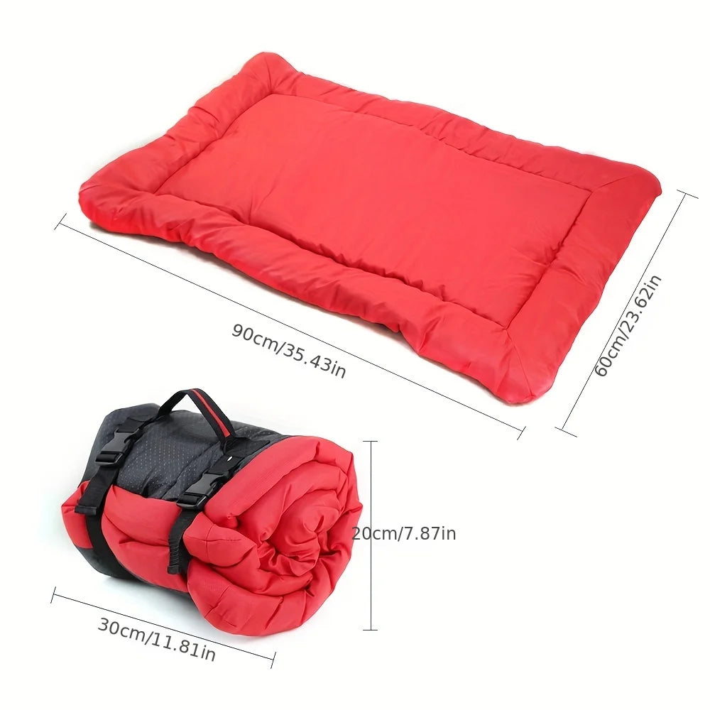 Red pet bed cushion, folded for storage with black carry straps