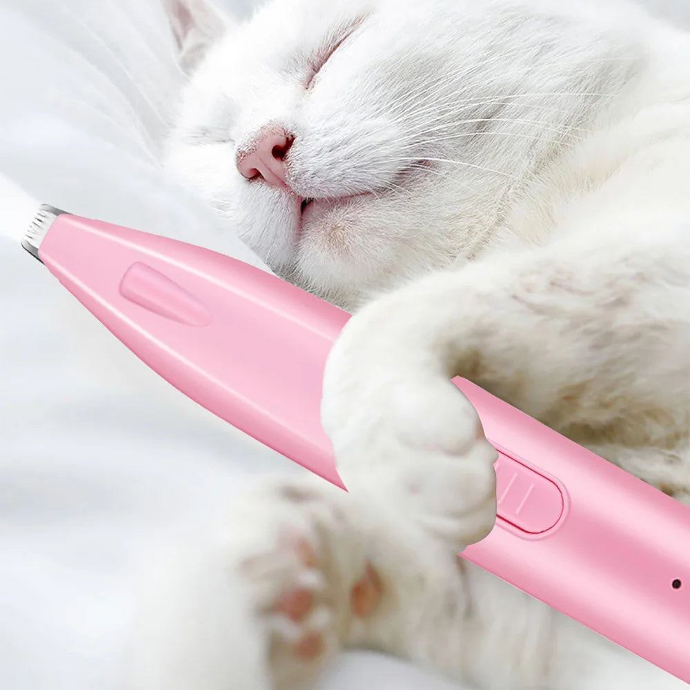 Pink electric pet hair trimmer held near a cat paw