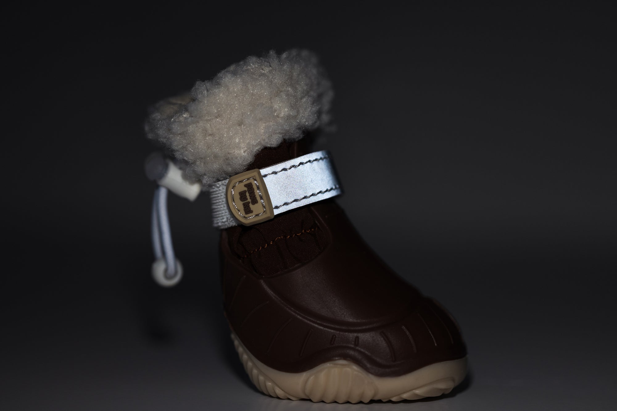 Single brown dog snow boot with cream fleece cuff, gray-blue strap, and rubber sole